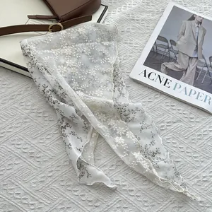 Detail of floral lace embroidery and wavy edges on white cotton linen neck scarf