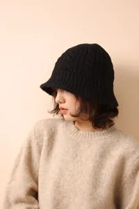 Detail of black merino wool fisherman hat with cable knit texture and warm autumn style