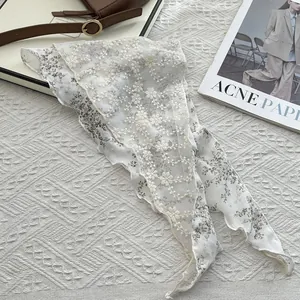 Close-up detail of white lace scarf with vintage floral embroidery and scalloped edges