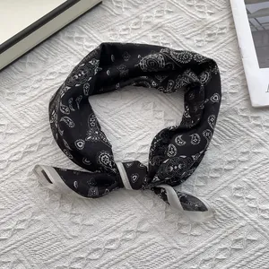 Detail of a black paisley silk scarf with a white border and knotted decorative styling