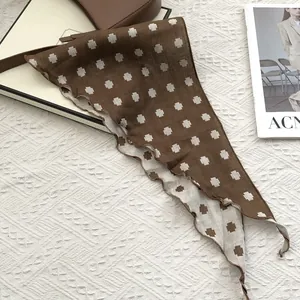 Detail view of brown cotton neck scarf with beige cross patterns and wavy stitched edges