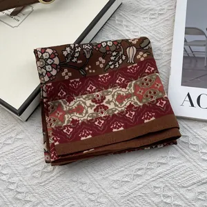 Vista detallada de un pañuelo de seda con estampado paisley sobre fondo blanco texturizado
