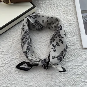Macro detail of silk-cotton neckerchief featuring classic black paisley and contrast border