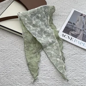 Detail of light green floral neckerchief with delicate lace embroidery and wavy edges