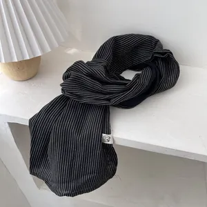 Détail de l'écharpe rayée noire et blanche en coton et lin avec étiquette logo
