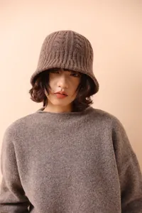 Close-up of brown merino wool knit bucket hat with textured cable pattern on a model