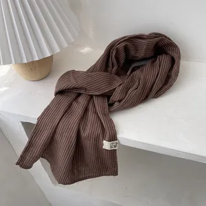 Détail d'une écharpe en coton à rayures marron avec texture naturelle et franges