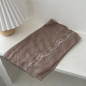 Detailed close-up of brown linen scarf with white embroidery in a cozy home setting