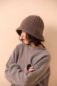 Detail of chunky cable knit texture on a brown merino wool bucket hat for winter