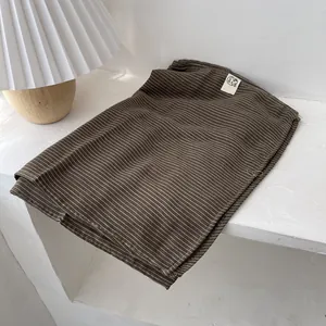 Détail d'une écharpe en coton et lin marron à rayures avec coutures nettes et étiquette tissée