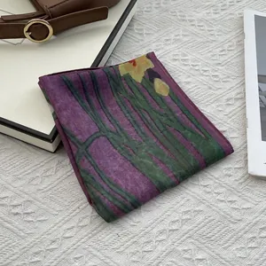 Close-up of a floral cotton scarf with purple base and green plant patterns on white fabric
