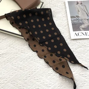 Detail of elegant black and brown cotton scarf with geometric cross patterns on white background