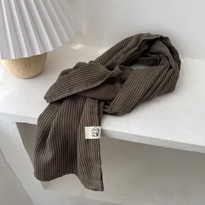 Vue détaillée de l'écharpe rayée marron foncé en coton et lin avec étiquette tissée