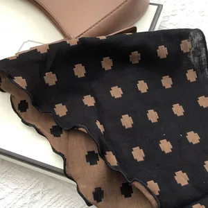 Detail of cotton square scarf with geometric print and decorative wavy stitched edges