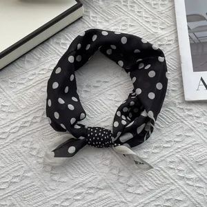 Detail of silk scarf tied in a bow featuring elegant black and white polka dot patterns