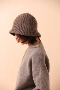 Detailed knit texture of dark brown merino wool fisherman hat with cable pattern