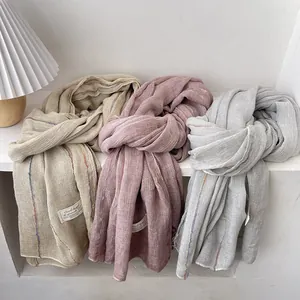 Detailed close-up of textured linen scarves in beige, pink and gray with striped pattern