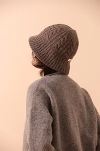 Detail of dark brown cable-knit merino wool fisherman hat with texture and white label