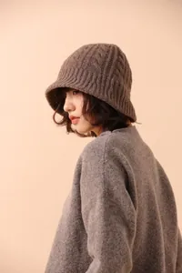 Detailed macro view of dark brown merino wool cable knit texture on a fisherman bucket hat