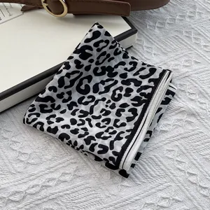 Classic black and white leopard print silk scarf with fine stitched edges on styled prop