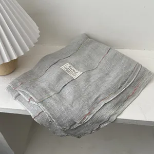 Detail shot of grey cotton linen scarf with texture weave and small brand woven label