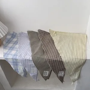 Set of minimalist plaid and striped cotton scarves neatly layered on white stone steps