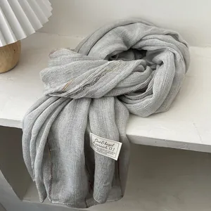 Detail of grey cotton linen scarf texture featuring contrast colorful stitching and tag