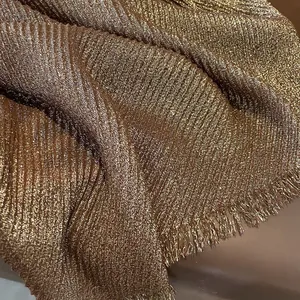 Macro shot of gold pleated linen scarf showing metallic texture and fringe details