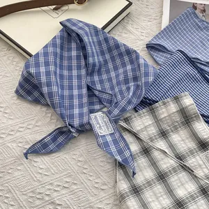 Detailed close-up of blue plaid cotton scarf with decorative lace label on white fabric