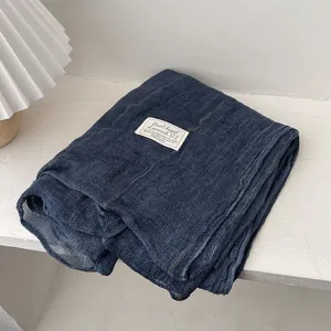 Detail of soft dark blue linen scarf featuring waffle texture and minimalist brand label