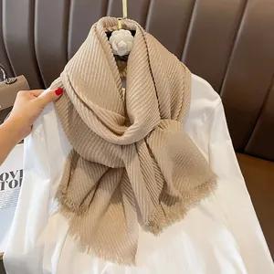 Detailed macro of gold foil linen scarf featuring elegant vertical pleats and fringe edges