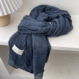 Detail of soft navy blue linen scarf with textured fabric and white brand label