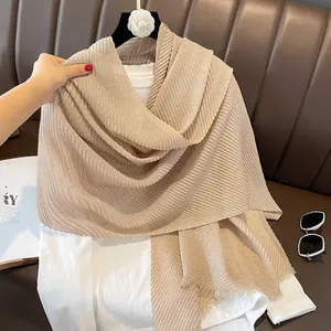 Detail of champagne gold pleated scarf with shimmering texture and fringe edges