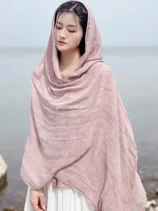 Detail of pink cotton linen scarf with soft texture draped by the sea as a shawl
