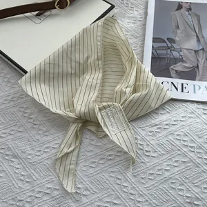 Close-up of vintage beige striped silk scarf with a minimalist stitched logo label