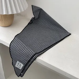 Classic black and white checkered cotton neckerchief with woven label on a white surface