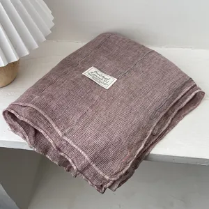 Close-up of dust pink linen scarf with subtle grid texture and brand fabric label
