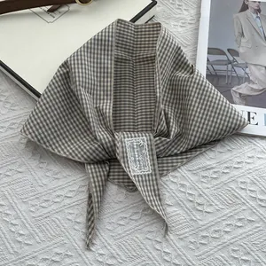Detail of checkered cotton scarf with neat stitching and an embroidered fabric label