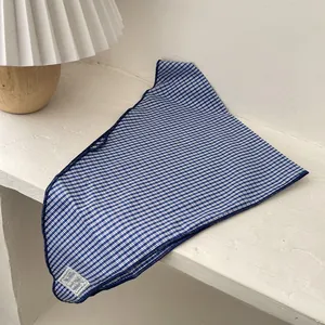 Detail of blue and white gingham cotton triangle scarf with decorative stitched label