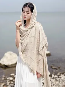 Detailed texture of beige linen scarf with thin colorful stripes against a scenic lake