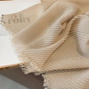 Macro shot of gold foil pleated cotton scarf with shimmer texture and fringe edges