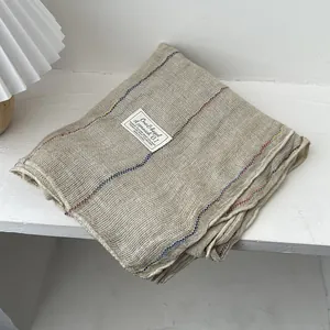 Detailed view of linen texture scarf with colorful stitching and minimalist brand label