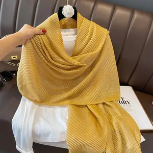 Macro detail of golden pleated shawl scarf with metallic sheen and shimmering fabric texture
