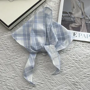 Detail of blue plaid cotton scarf with white lace embroidery label on knit background