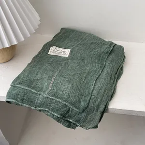 Detail of sage green textured cotton linen blanket with a woven label and soft ridges
