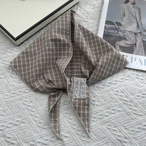 Close-up of vintage brown plaid bandana with white embroidered label on knit background