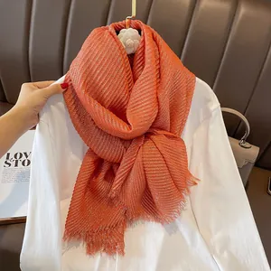 Detail showing orange pleated linen scarf with shimmering gold thread and fringe edges