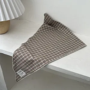 Detailed view of brown plaid triangle headscarf with sewn label and overlock edge