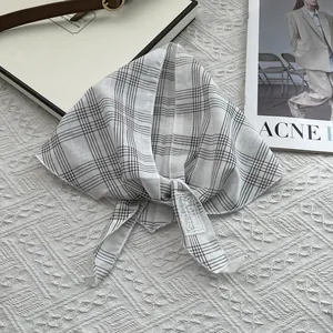 Detail of grey and white checkered cotton neckerchief with woven label on soft background