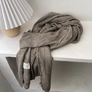 Detail showing soft cotton linen scarf texture with decorative stitching and tag